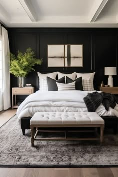 a bedroom with black walls, white bedding and an ottoman in front of the bed