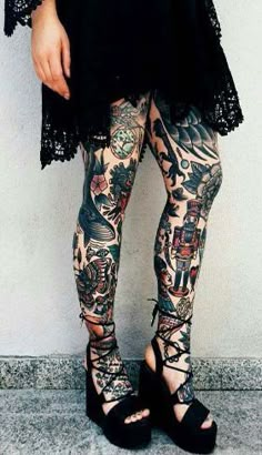 a woman with tattoos on her legs and leggings is standing in front of a wall