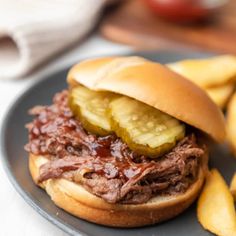 a pulled pork sandwich with pickles on a plate