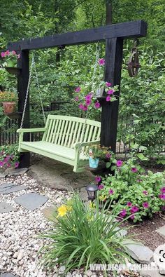 a green bench sitting in the middle of a garden next to some flowers and plants