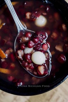 a spoon full of soup with cranberries and an egg