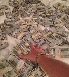 a person laying on top of a bed covered in lots of money next to each other