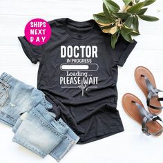 "Funny Doctor Shirt, Future Doctor Tee, Doctor In Progress T-Shirt, Medical School Shirt, Doctor In Training Tee, Gift For New Doctor Tee -- How To Order --- 1-) Please check and review all photos in the listing 2-) Choose your t-shirt color and size *Different styles of shirts may have different shades of same color choice due to different manufacturer brands. *For this reason, we recommend you to order same style of shirts (Unisex, Tank Top, etc.) if you want exact matching colors. 3-) Enter y Doctor T Shirt Design, Doctor In Progress, Future Doctor, Cotton Polyester Fabric, Matching Colors, Same Style, Tank Top Designs