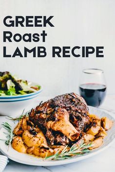 a white plate topped with meat next to a bowl of salad and a glass of wine