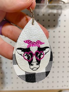 a hand holding a keychain with a cow wearing glasses on it's face