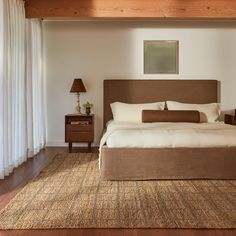 a large bed sitting on top of a wooden floor next to a white curtained wall