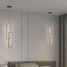 a bed sitting under three hanging lights next to a lamp on the side of a wall