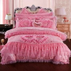 a pink bed with ruffled bedspread and matching comforter in a bedroom