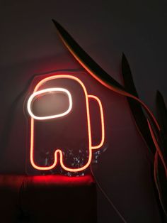 a neon sign with an elephant on it next to a potted plant in a dark room