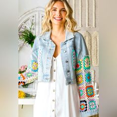 a woman standing in front of a white wall wearing a denim jacket with crocheted details