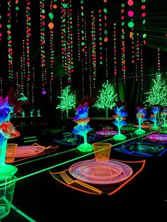 an illuminated room with flowers and vases on the tables in front of colorful lights