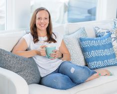 a woman sitting on a couch holding a cup