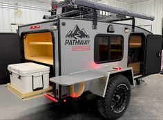 an off road camper trailer with the door open and cooler attached to it's side