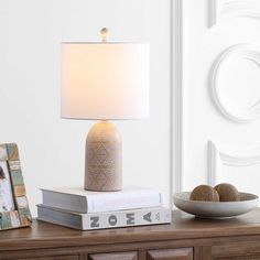 a table with a lamp on top of it next to some books and a bowl