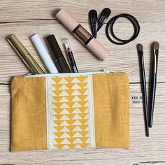 the contents of a make - up bag laid out on a wooden table with brushes and makeup