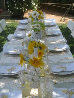 the table is set with sunflowers and clear vases on it's sides