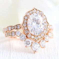 a close up of a diamond ring on a white surface with flowers in the background