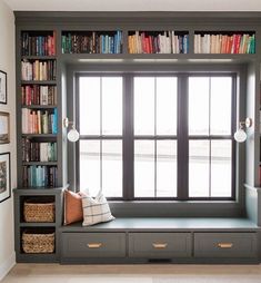 a window seat in front of a bookshelf filled with lots of bookcases