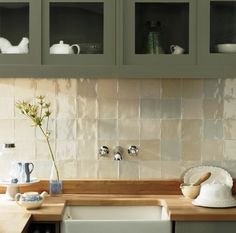 a kitchen with green cabinets and white dishes on the counter top, along with an oven