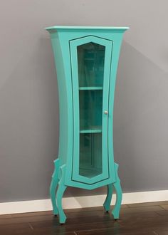 a tall blue cabinet sitting on top of a hard wood floor next to a wall