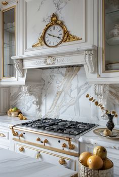 a kitchen with marble counter tops and gold trim around the stove top, along with an ornate clock mounted on the wall