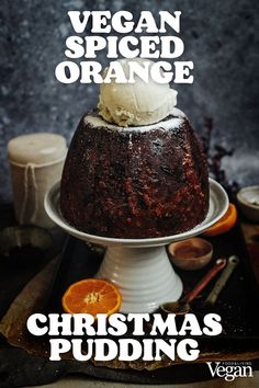 vegan spiced orange christmas pudding on a white cake platter with an orange slice