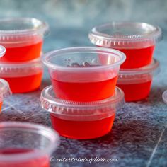 plastic cups filled with red liquid sitting on top of a table