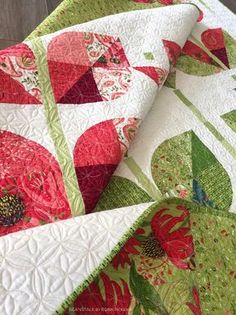 a close up view of a quilt on a table top with red and green flowers