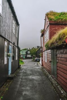 an alley way between two buildings with grass growing on the roof and one building that has a green roof