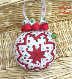 a red and white ornament hanging from a wicker basket with a bow