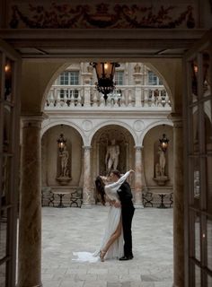 a bride and groom kissing in front of an ornate archway at the end of their wedding day