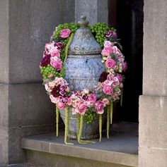 a large vase with flowers and grapes on the outside of it, sitting in front of a doorway