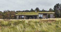 an old building with a green roof in the middle of a grassy field next to trees