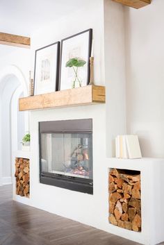 a fireplace with logs stacked on top of it and framed pictures above the fire place