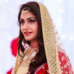 a woman wearing a red and gold bridal outfit with her hair in a bunt