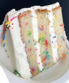 a slice of cake with white frosting and multicolored sprinkles