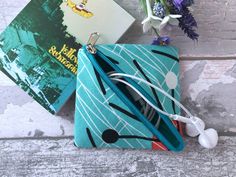 a blue purse sitting on top of a wooden floor next to a book and headphones