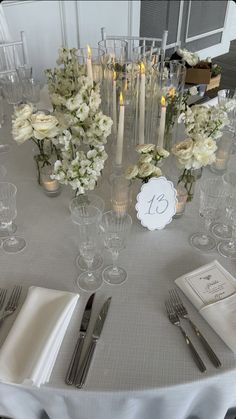 the table is set with silverware and white flowers