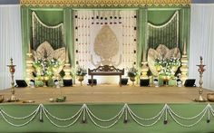 a stage set up for a wedding ceremony with white and green decorations on the side