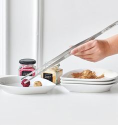 a person cutting food with a large knife on top of it next to some plates