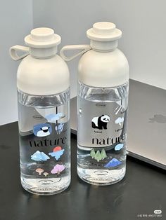 two water bottles sitting on top of a table next to an apple computer and mouse