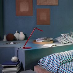 a bedroom with blue walls and checkered bedding on the bottom shelf is lit by a red lamp