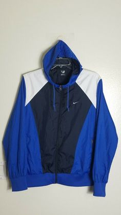 This is a men's Nike Athletic Dept. blue, black, and white color block full zip front hoodie windbreaker / jacket. There is a ribbed stretch hemline as well as the cuffs at each wrist, 2 zip closure pockets with a hook and loop closure pocket on the inside, and the Nike Swoosh is embroidered at the left chest. The measurements lying flat are: Chest 24, neck 9, shoulder to shoulder 19, arm length 26, and length from top of the shoulder to hem is 28". Nike Hoodie Track Jacket For Streetwear, Hooded Sport Coat With Detachable Hood For Streetwear, Hooded Sport Coat With Adjustable Hood For Streetwear, Hooded Urban Sport Coat For Streetwear, Urban Hooded Sport Coat For Streetwear, Streetwear Hooded Sport Coat With Adjustable Hood, Streetwear Sport Coat With Adjustable Hood, Nike Hooded Track Jacket For Streetwear, Urban Nylon Hooded Sport Coat