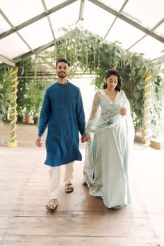 a man and woman holding hands walking down a walkway