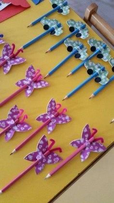 several pencils with butterflies on them sitting on a yellow table cloth covered in paper