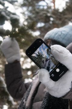 a person holding up a cell phone in the snow