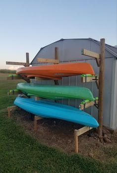 three surfboards are stacked on top of each other in front of a building with a metal roof