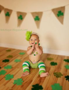 a baby is sitting on the floor with shamrock decorations