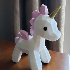 a paper mache of a pink and white unicorn on top of a wooden table