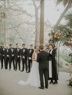 a bride and groom standing in front of their wedding party at the end of an outdoor ceremony